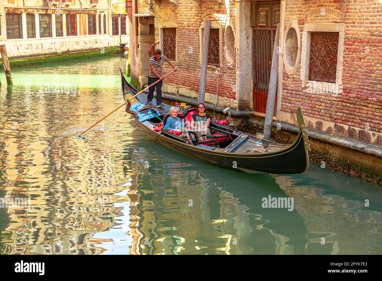 Venice, Italy - May 9, 2021: Traditional Gondoliers in Venice taking tourists on tour on historic Grand Canal of city. People with mask for Stock Photo