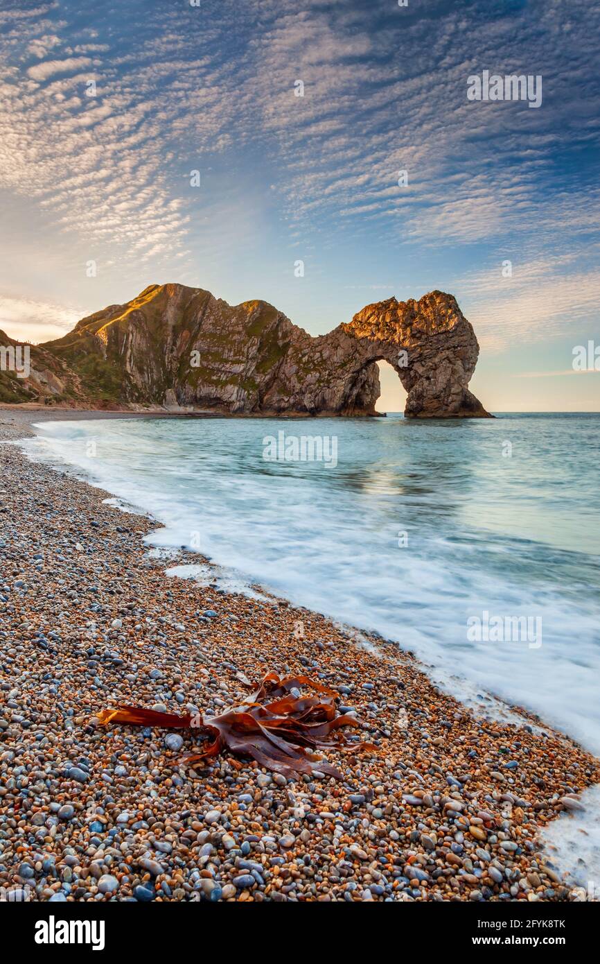 Sunrise at the wonderful Durdle Door in Dorset, with a mackerel sky. Stock Photo