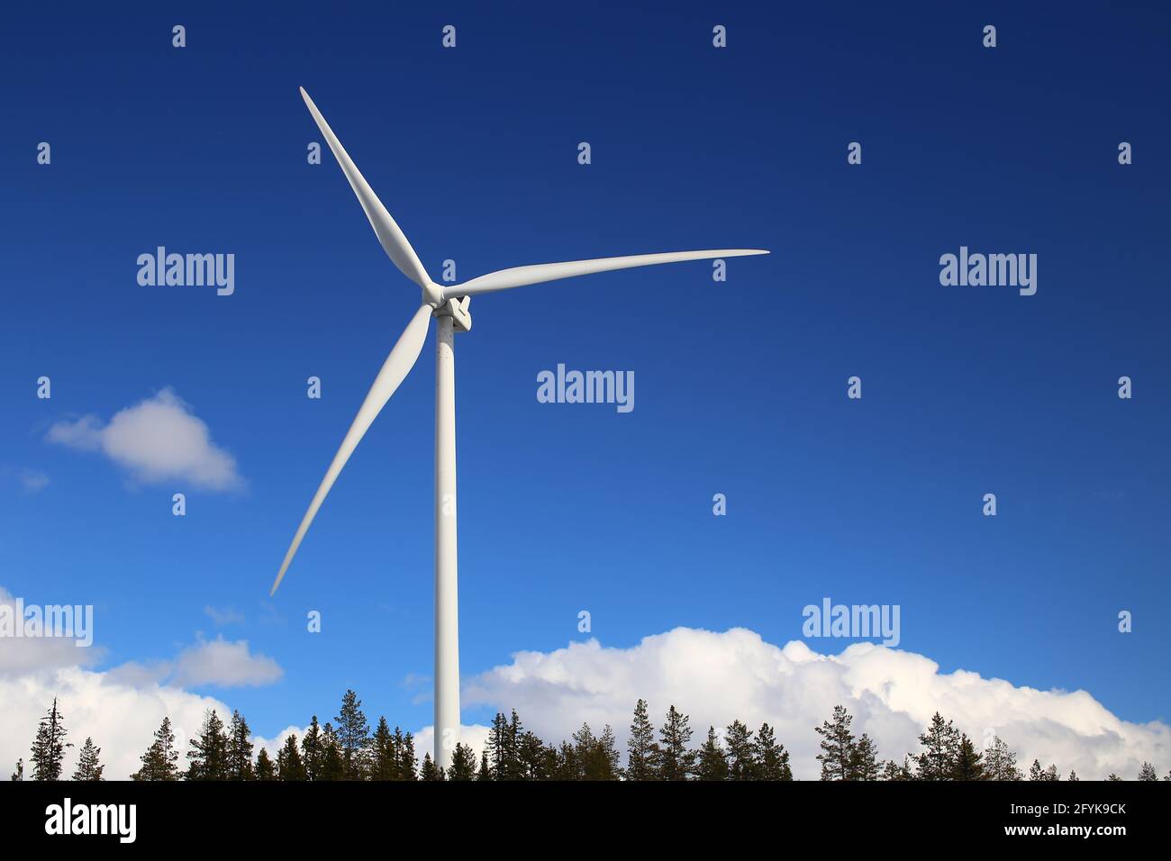 Wind turbine over forest and clouds with blue sky Stock Photo - Alamy