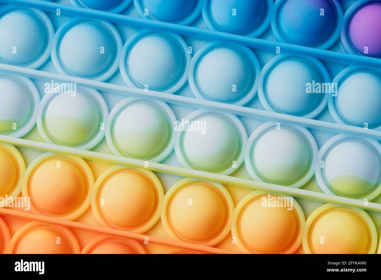 Close up of Pop it toy silicone background texture. Rainbow Hues colors. fidget push pop anti-stress sensory toy. Autism Special Stock Photo