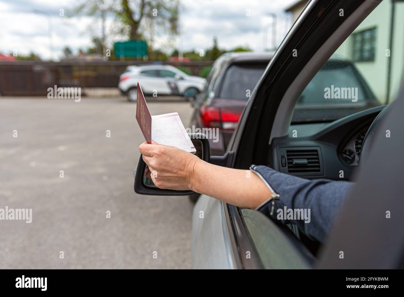 women hand through car window giving passport for customs control, driver with an identity card in a car at a border checkpoint Stock Photo