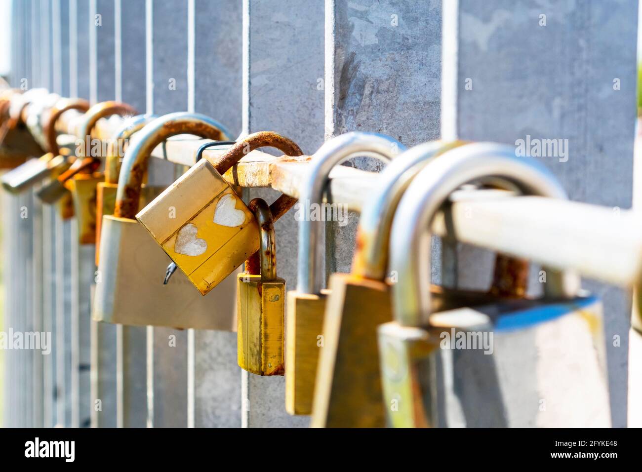 Golden padlock with a couple of hearts scrawled. A pair of rusty old coupled locks among many others as a symbol of love forever. Ancient wedding trad Stock Photo