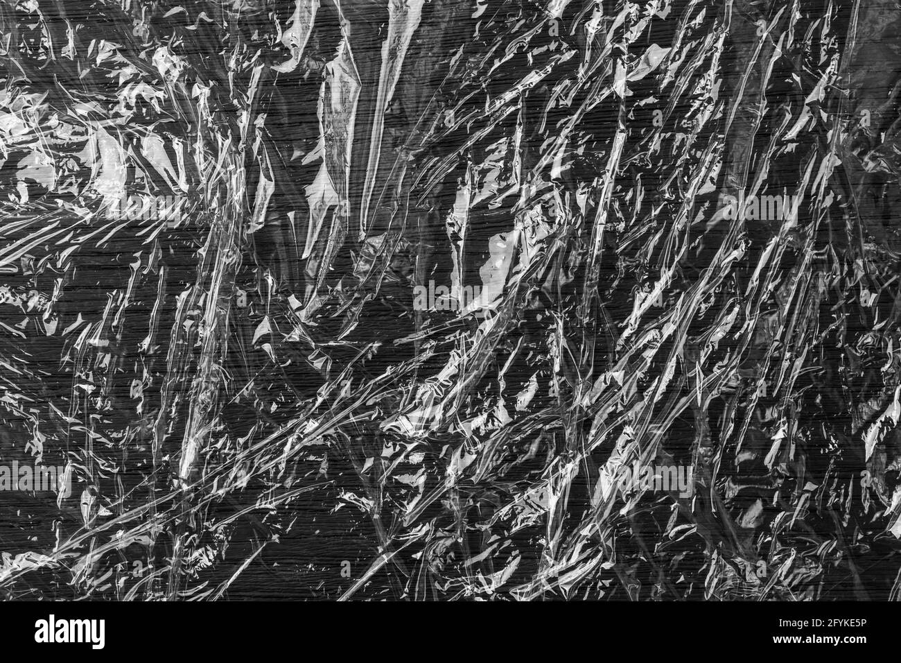 Black glued crumpled shiny grunge plastic. Wrinkled polyethylene film