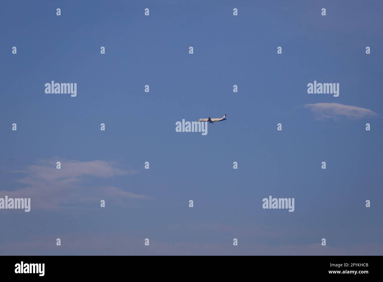 Propeller plane lit by the sun against a blue sky with white clouds and ...