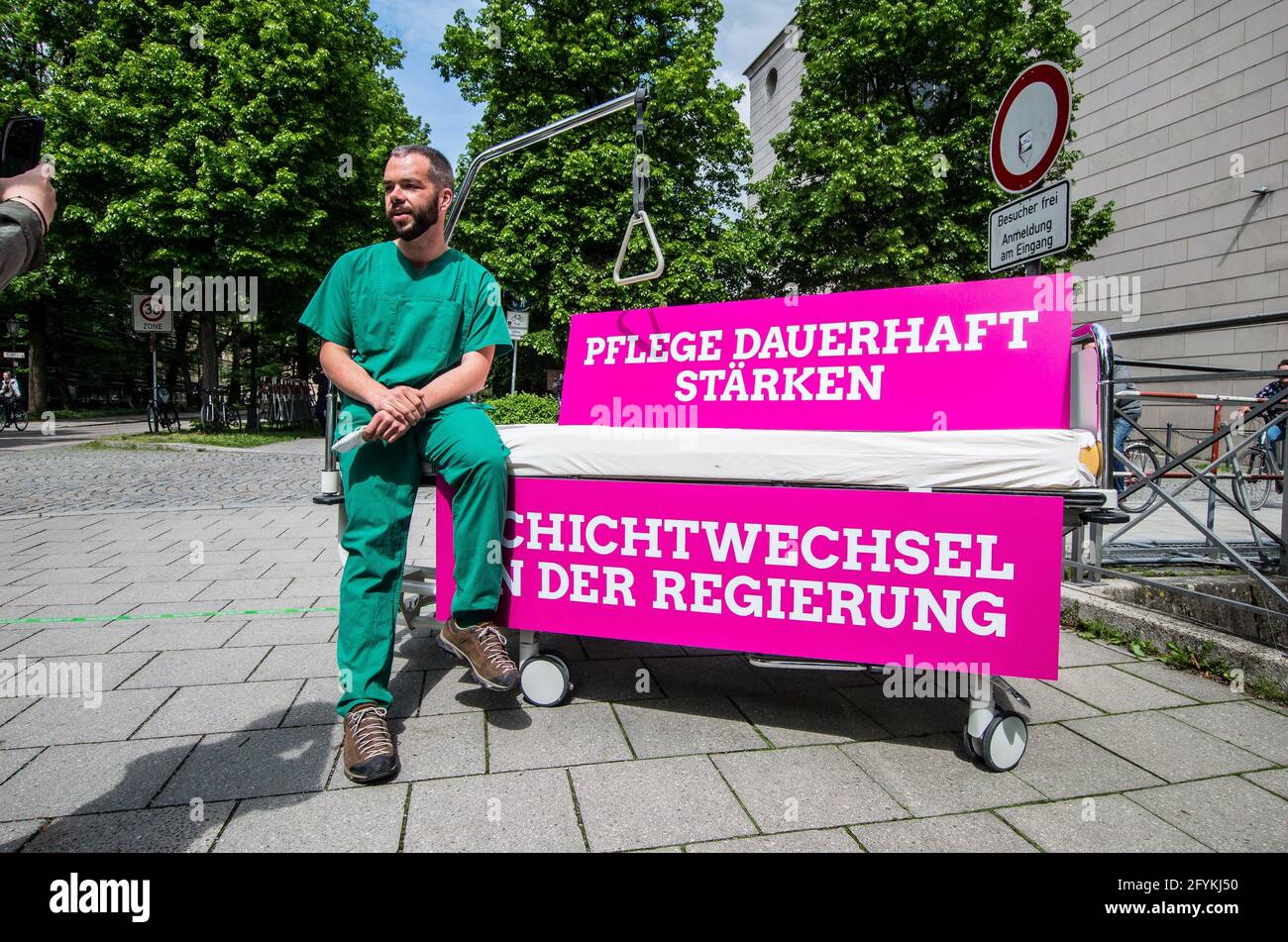 Munich, Bavaria, Germany. 28th May, 2021. ANDREAS KRAHL of the Bavarian Greens wearing his hospital scrubs Kahl works in an Intensive Care Unit in Murnau and detailed the poor treatment of the healthcare workers by the Bavarian government that promotes overwork, poorer care quality, and burnout syndrome. The Bavarian Greens (die Gruenen/Buendnis90) organized a protest action at the Bavarian Staatskanzlei (government building) in support of healthcare workers. During the Coronavirus crisis, the working conditions for this sector have come into greater focus and The Greens are pushing for bette Stock Photo