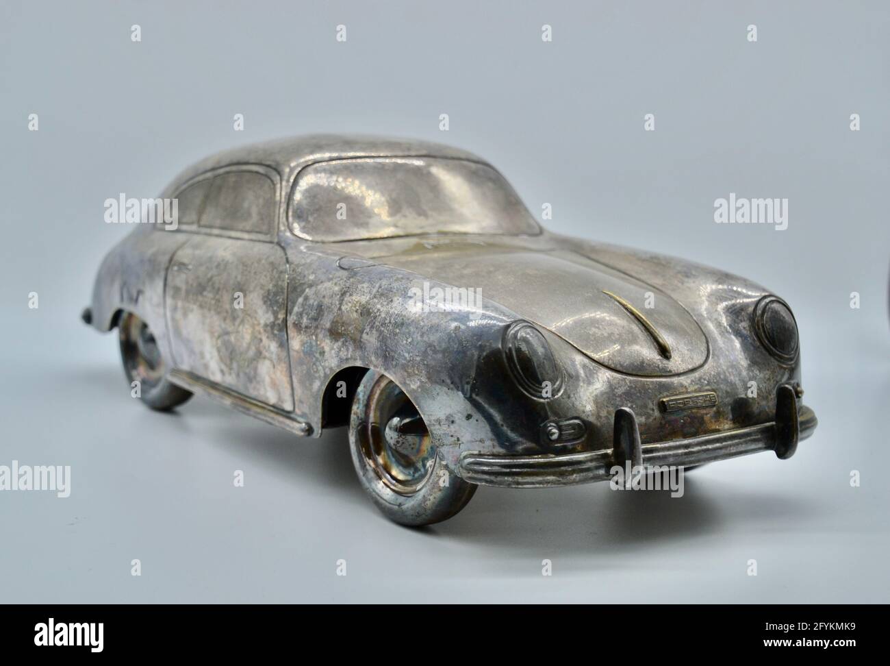 Silver tarnished vintage toy scale model of a Porsche 356 sports car in studio shot on white background Stock Photo