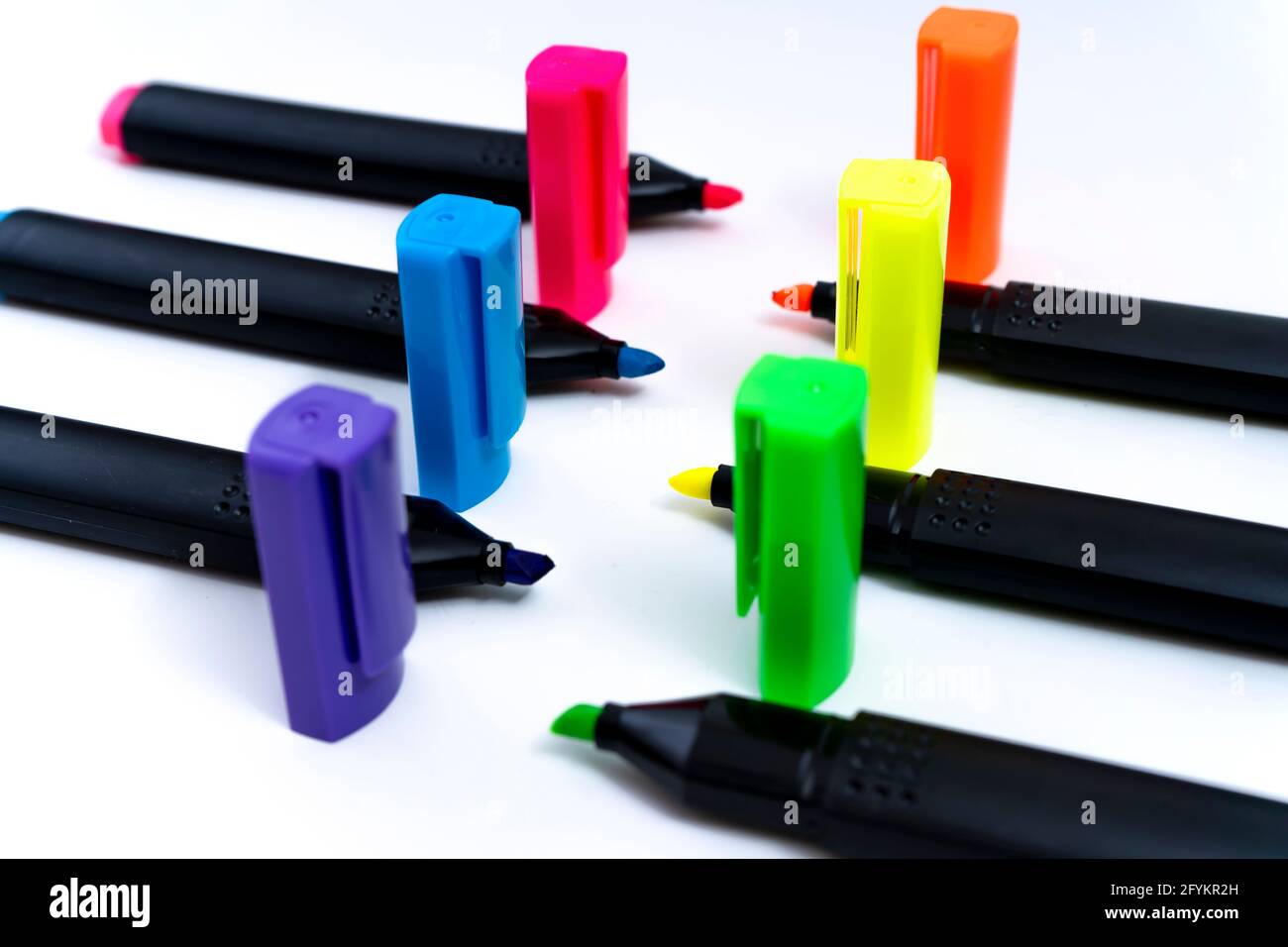 Set of uncovered color-ordered highlighters facing each other on white background. Stock Photo