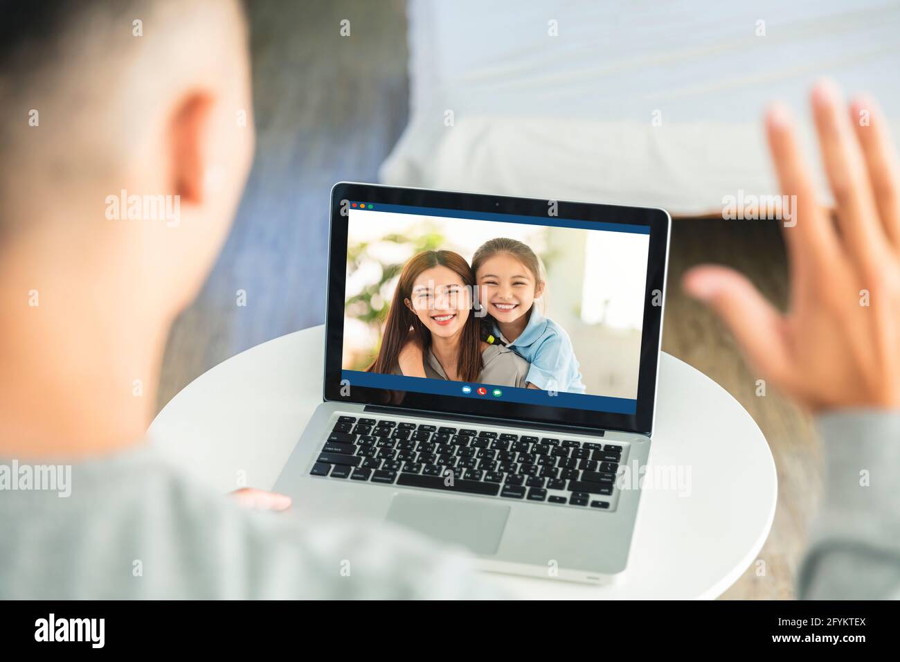 Young man speaking to wife and lovely daughter remotely, using laptop to talk to family online from home. Distance communication during coronavirus lo Stock Photo