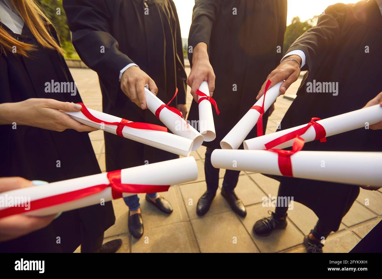 University or college graduates join diplomas standing in circle at graduation party Stock Photo