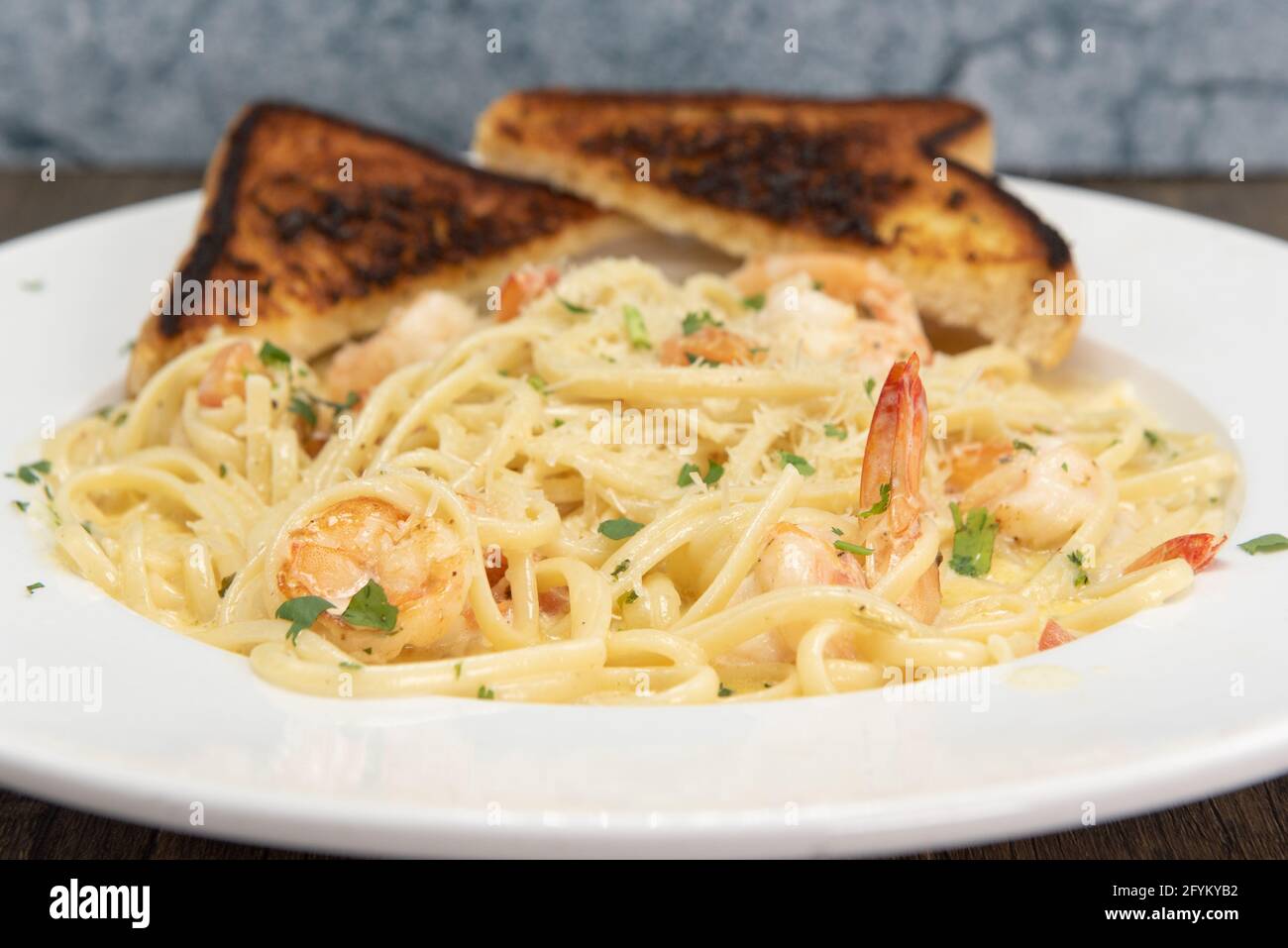 Shrimp scampi in buttery sauces and pasta served on a plate with grilled toast for a hearty appetite. Stock Photo