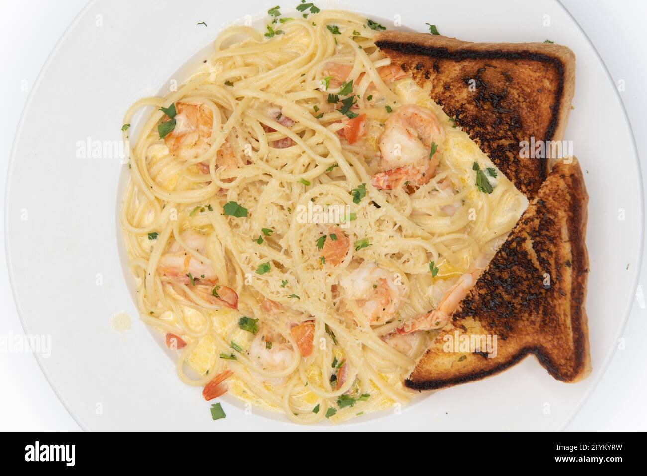 Overhead view of shrimp scampi in buttery sauces and pasta served on a plate with grilled toast for a hearty appetite. Stock Photo