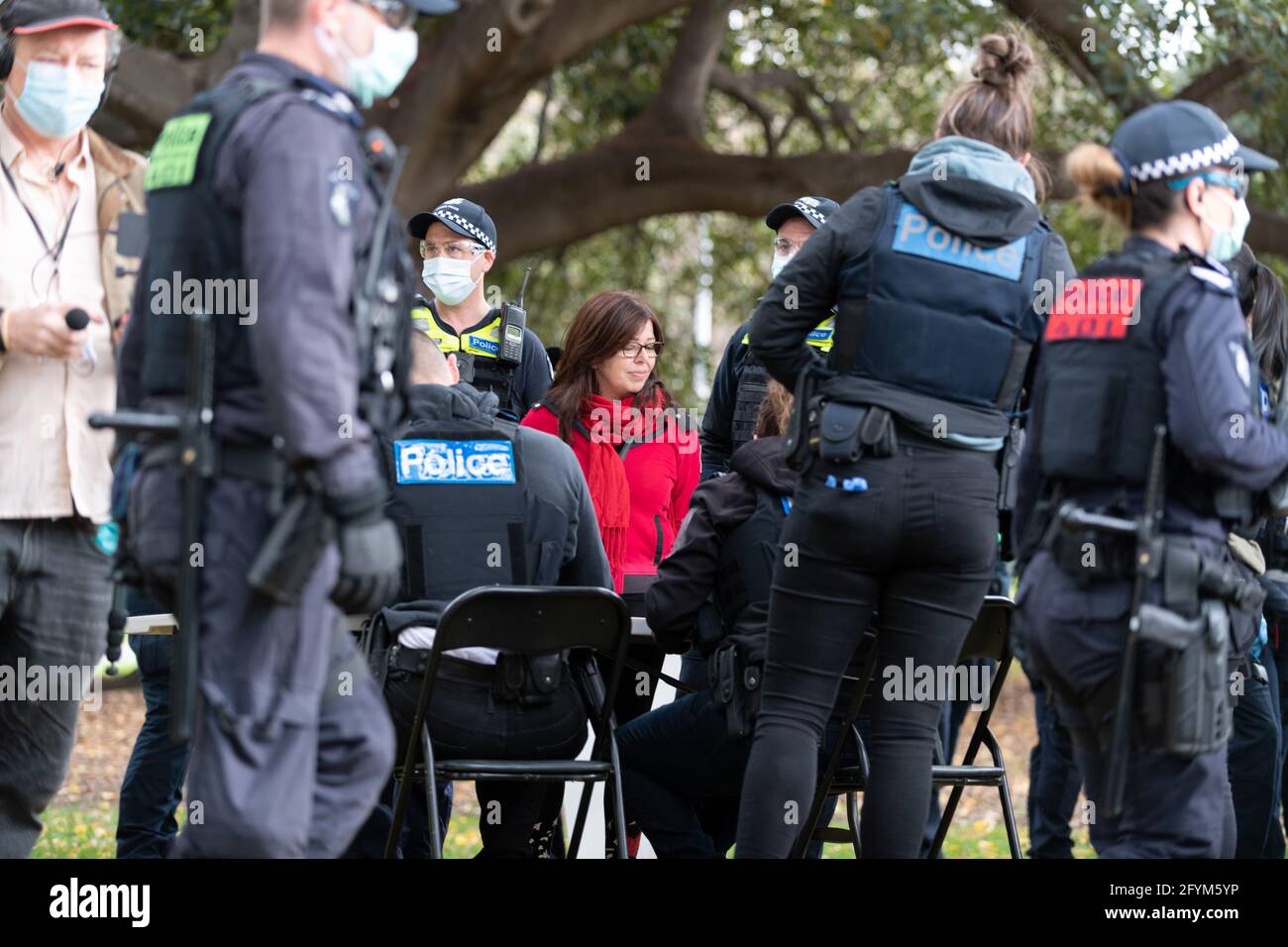 Melbourne, Australia 29 May 2021, A protester in red is processed by police officers in the park during a planned "Millions March" rally at Flagstaff Gardens, that had been canceled by organisers due to the snap lockdown. Hardcore anti-lockdown and anti-vaccination protesters still attend the park and rallied against the government. Credit: Michael Currie/Alamy Live News Stock Photo