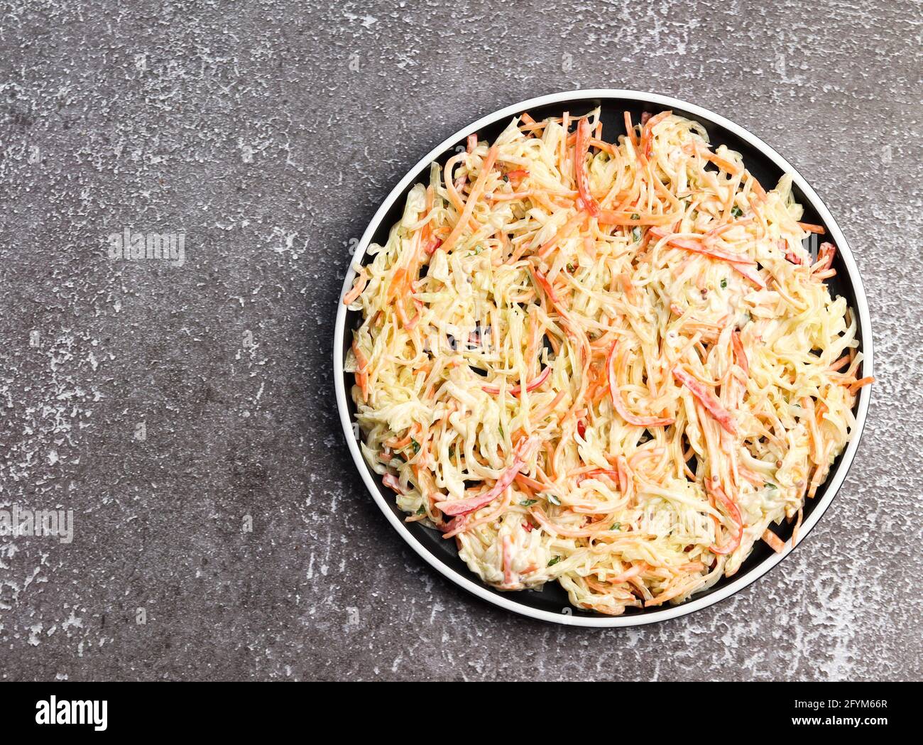 Fresh coleslaw salad on a round plate on a dark background. Top view, flat lay Stock Photo