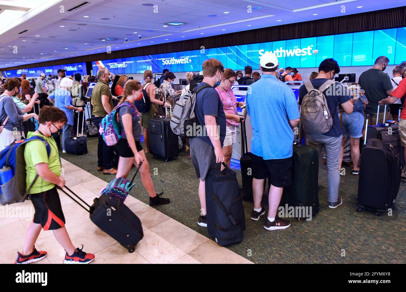 Travelers wait in line to check in at the Southwest Airlines ticket counter  at Orlando International Airport on the Friday before Memorial Day. As more  and more people have received the COVID-19