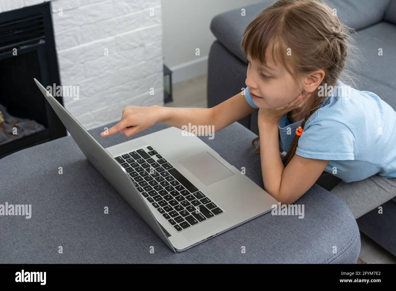 Distance learning. Cheerful little girl girl in headphones using laptop ...