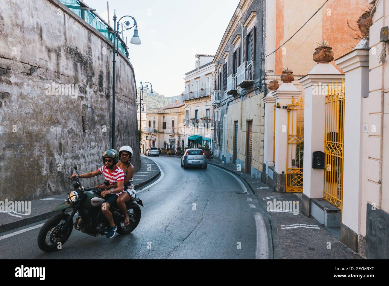 Massa Lubrense, Italy - August 23 2020: Man and Woman Riding a Motorcycle in the Via Roma Street in Summer on the Sorrentine Coast. Stock Photo