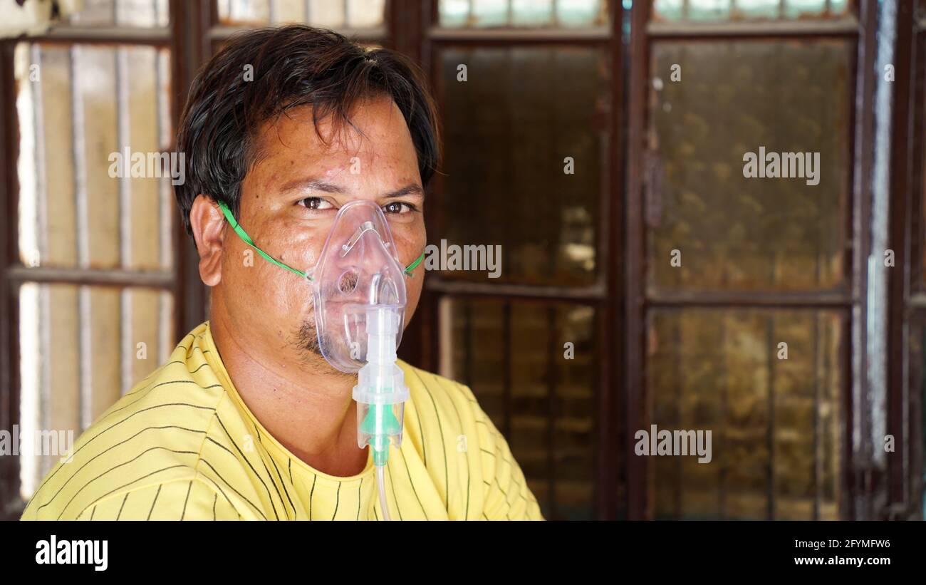 Jaipur, India - May 21: Close up sick Yong boy with face oxygen mask with liquid Oxygen flow outside of hospital. Boy infected with Covid 19 disease. Stock Photo