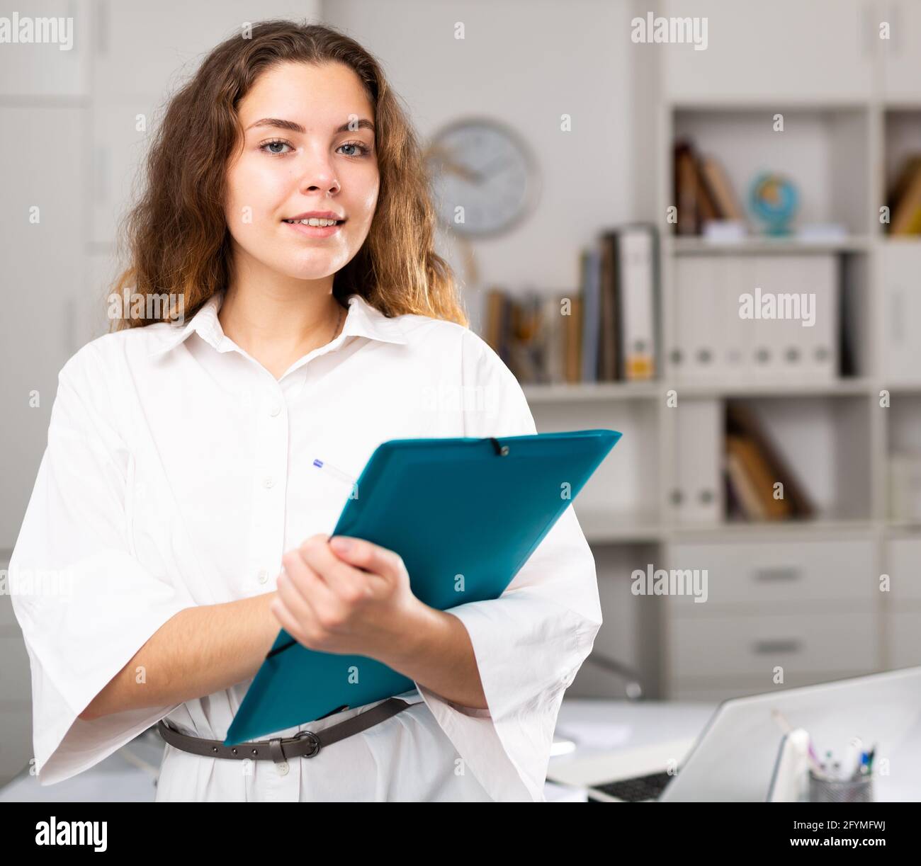 Closeup portrait of smiling young american woman holding folder and pen ...