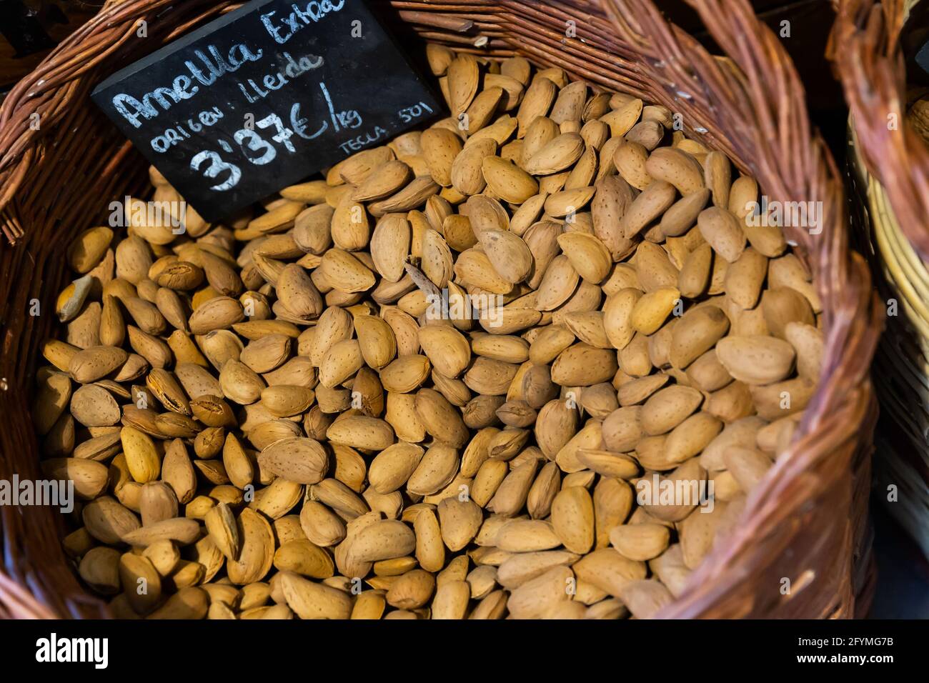 Closeup of dried almonds in shell in wicker basket with price tag in Catalan  for sale on market Stock Photo - Alamy