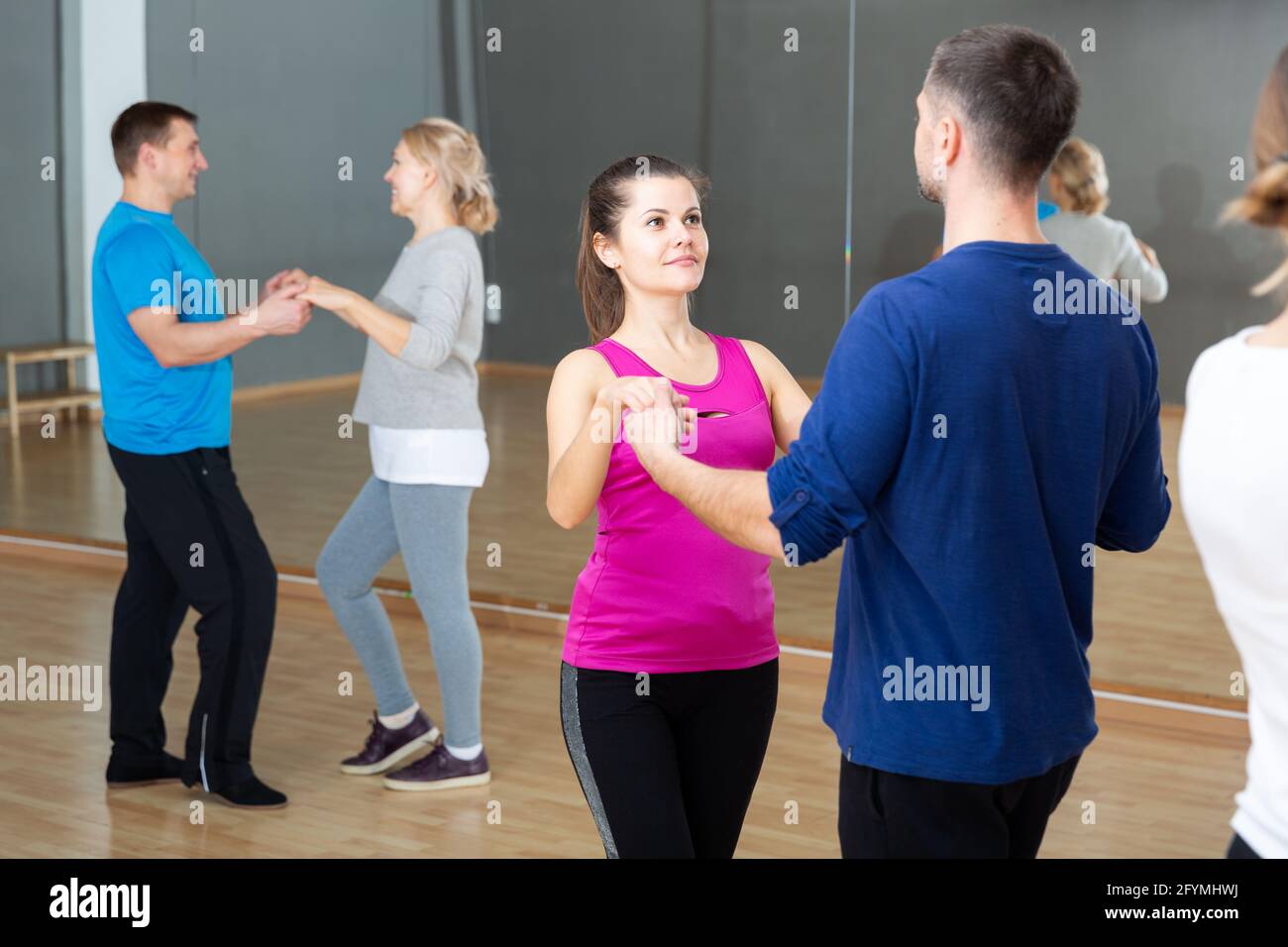 Group of happy adult people dancing modern social dances in pair at