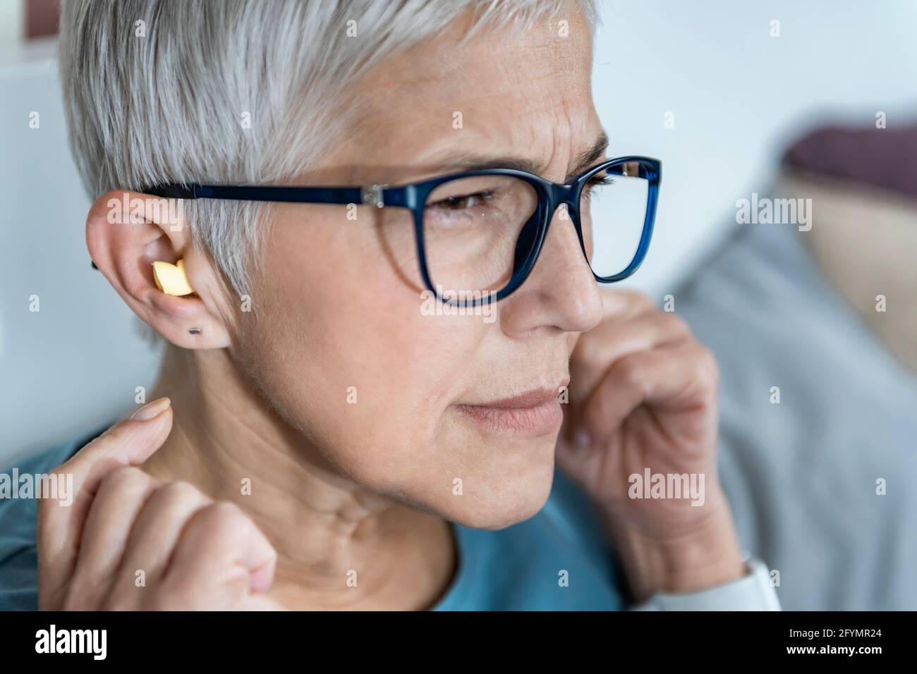 Mature woman using earplugs for sleeping Stock Photo