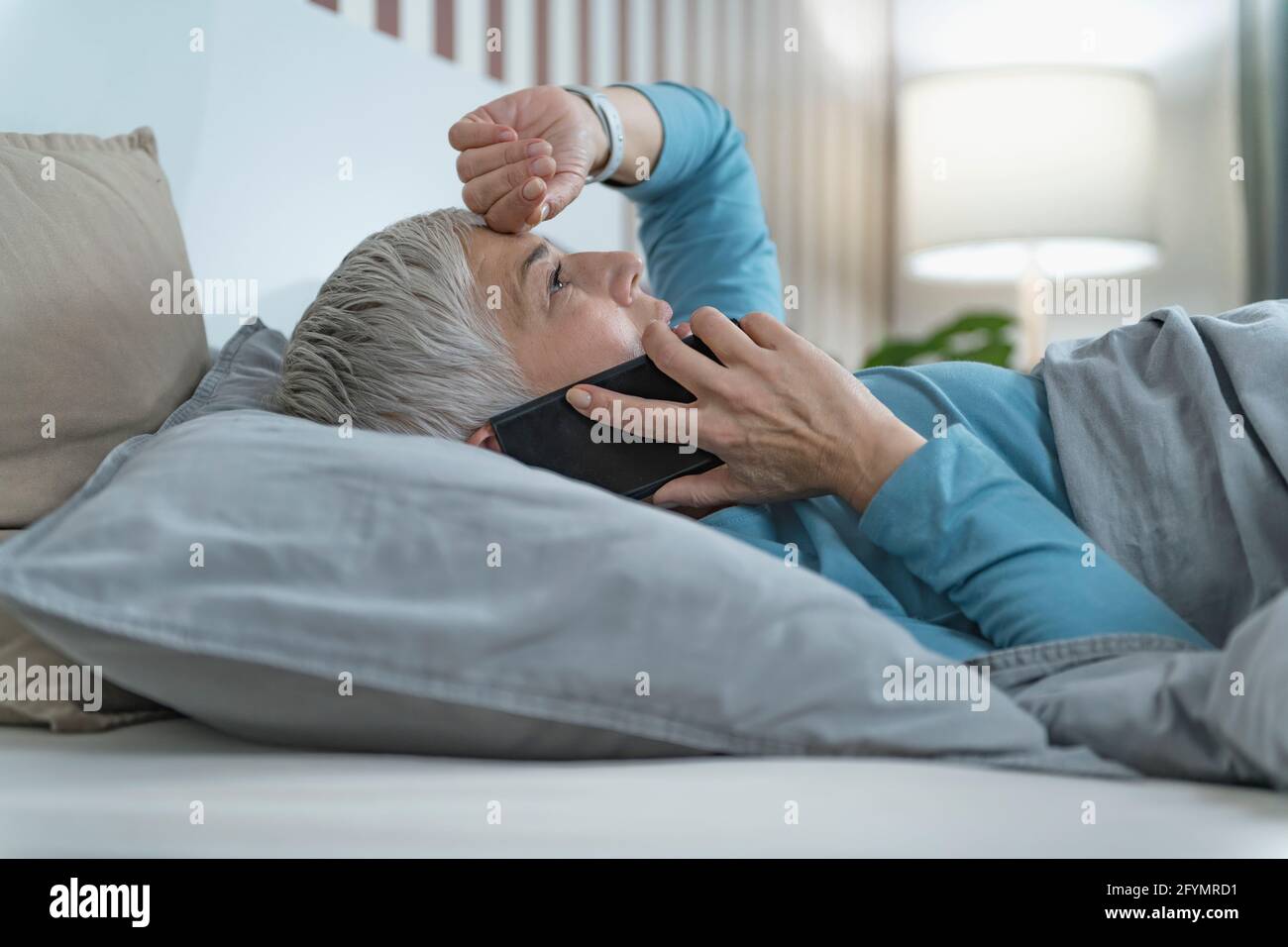 Woman using smartphone in bed Stock Photo