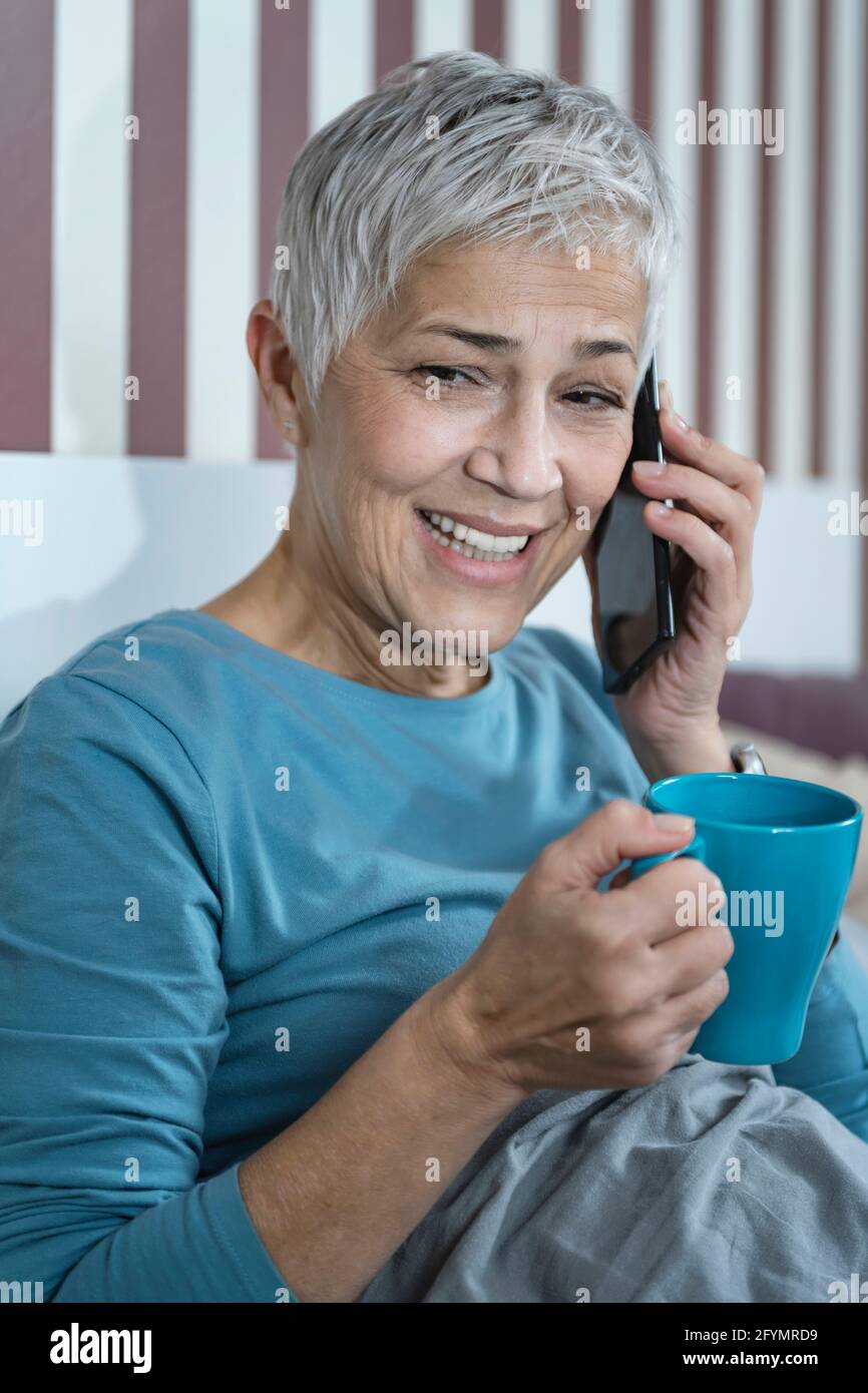 Woman using smartphone in bed Stock Photo