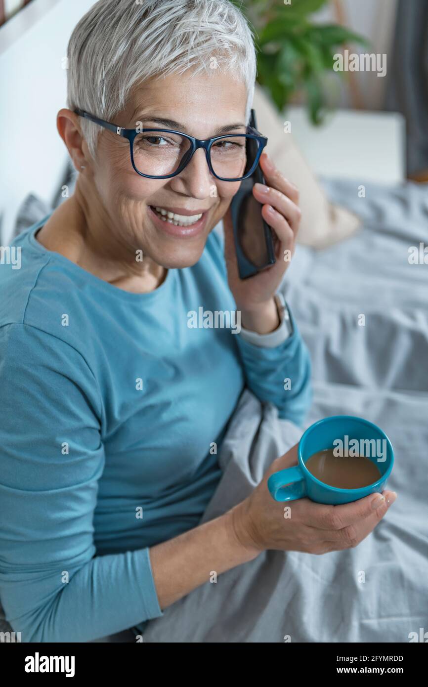 Woman using smartphone in bed Stock Photo