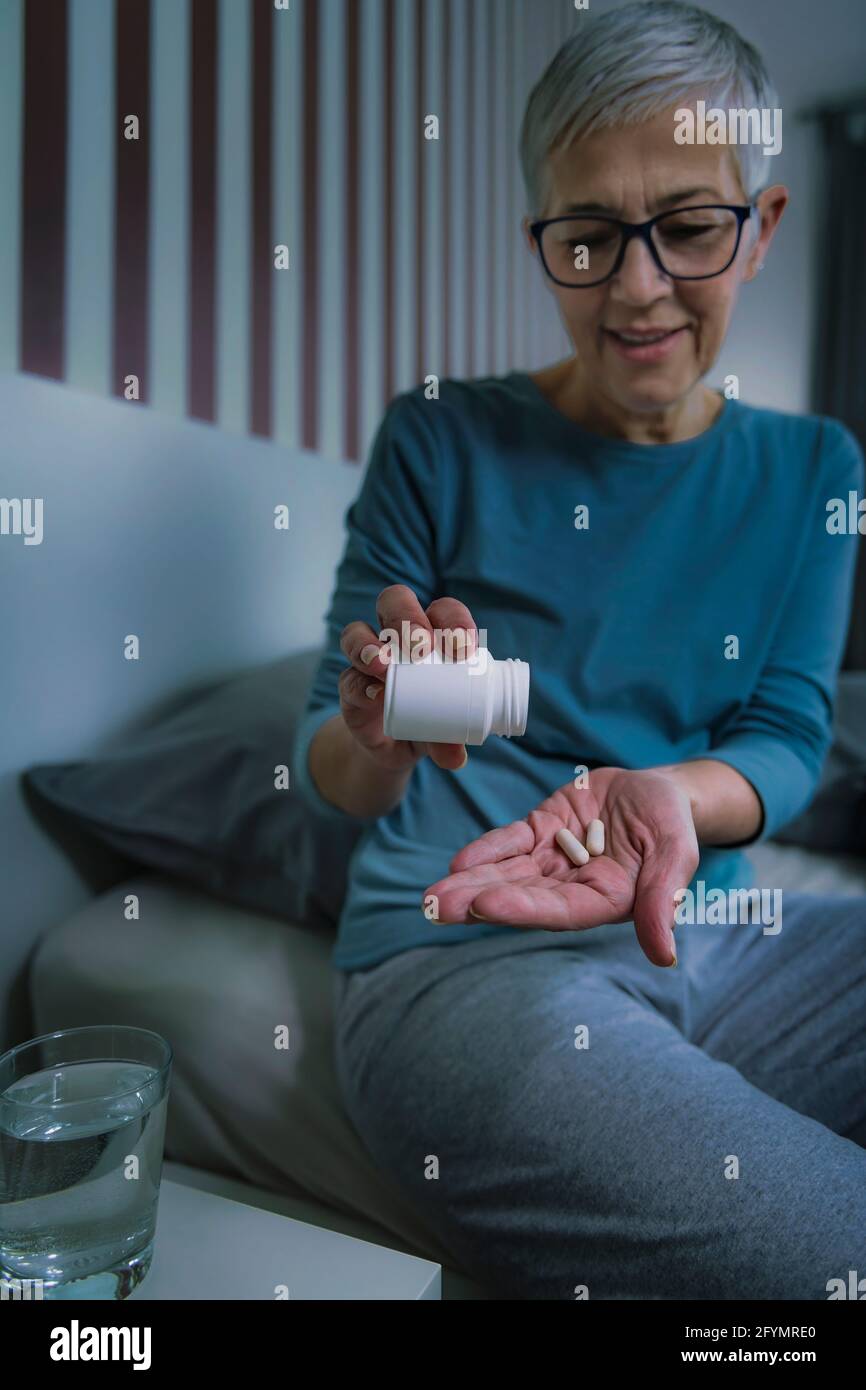 Woman taking melatonin pills Stock Photo