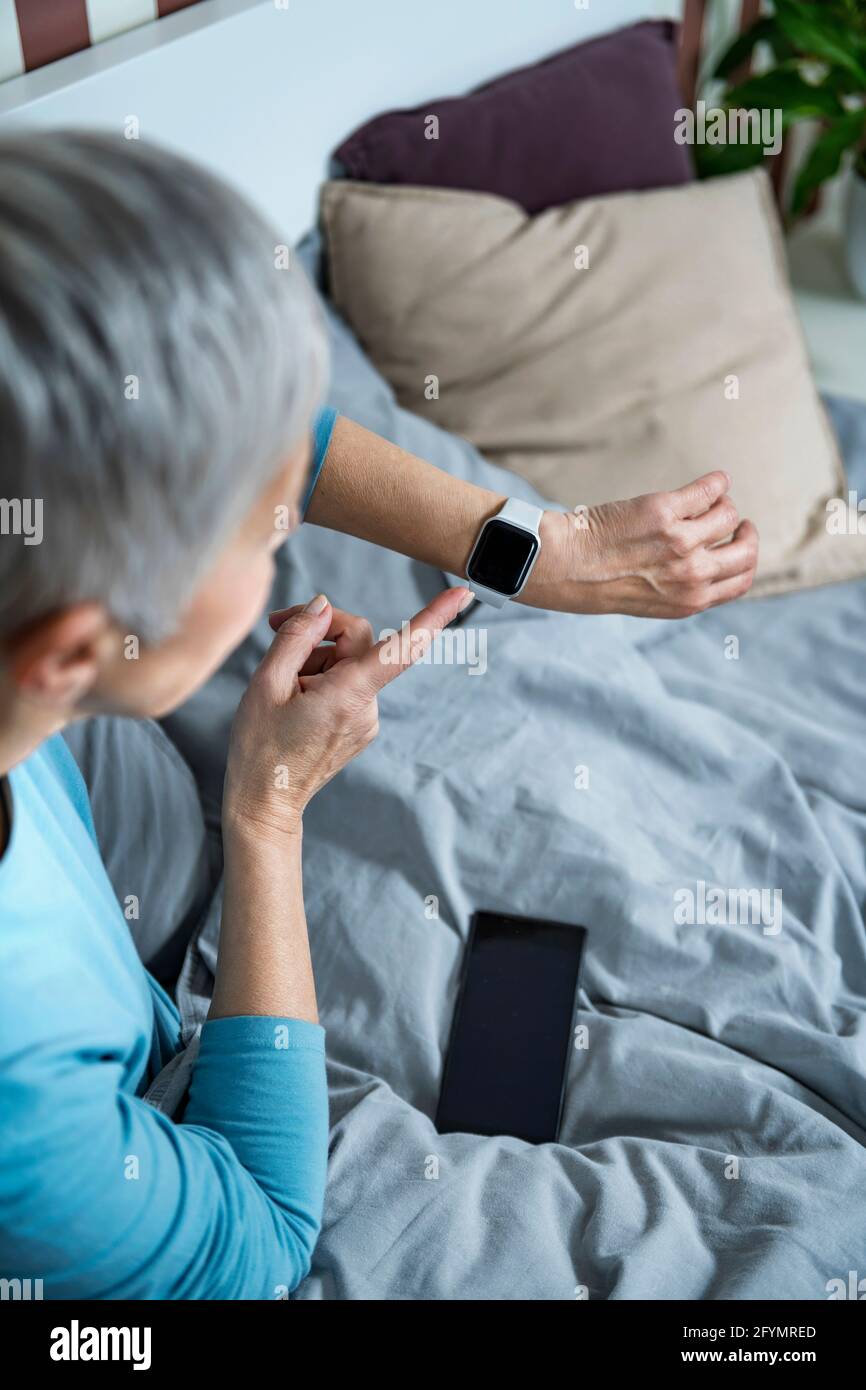 Senior woman checking smart watch sleep tracker Stock Photo