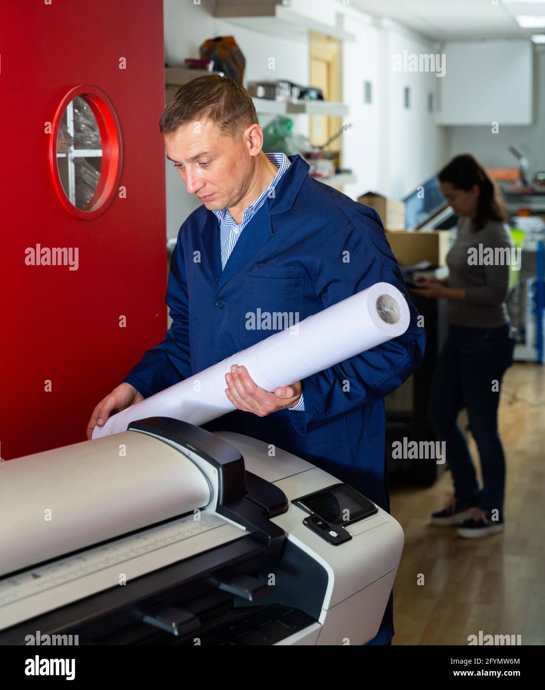 Repairman changes paper roll in plotter Stock Photo Alamy