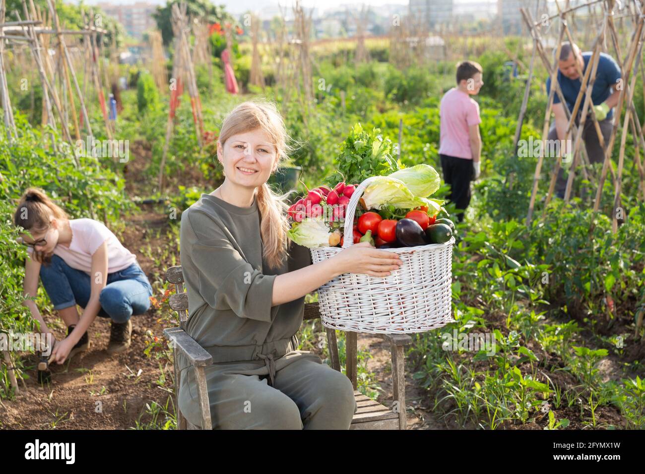 Positive young adult woman posing with basket full of harvested