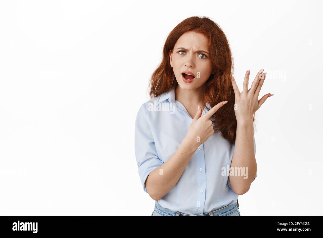 Angry girlfriend pointing at finger without ring, wants to get married, having fight with boyfriend about marriage and proposal, standing against Stock Photo