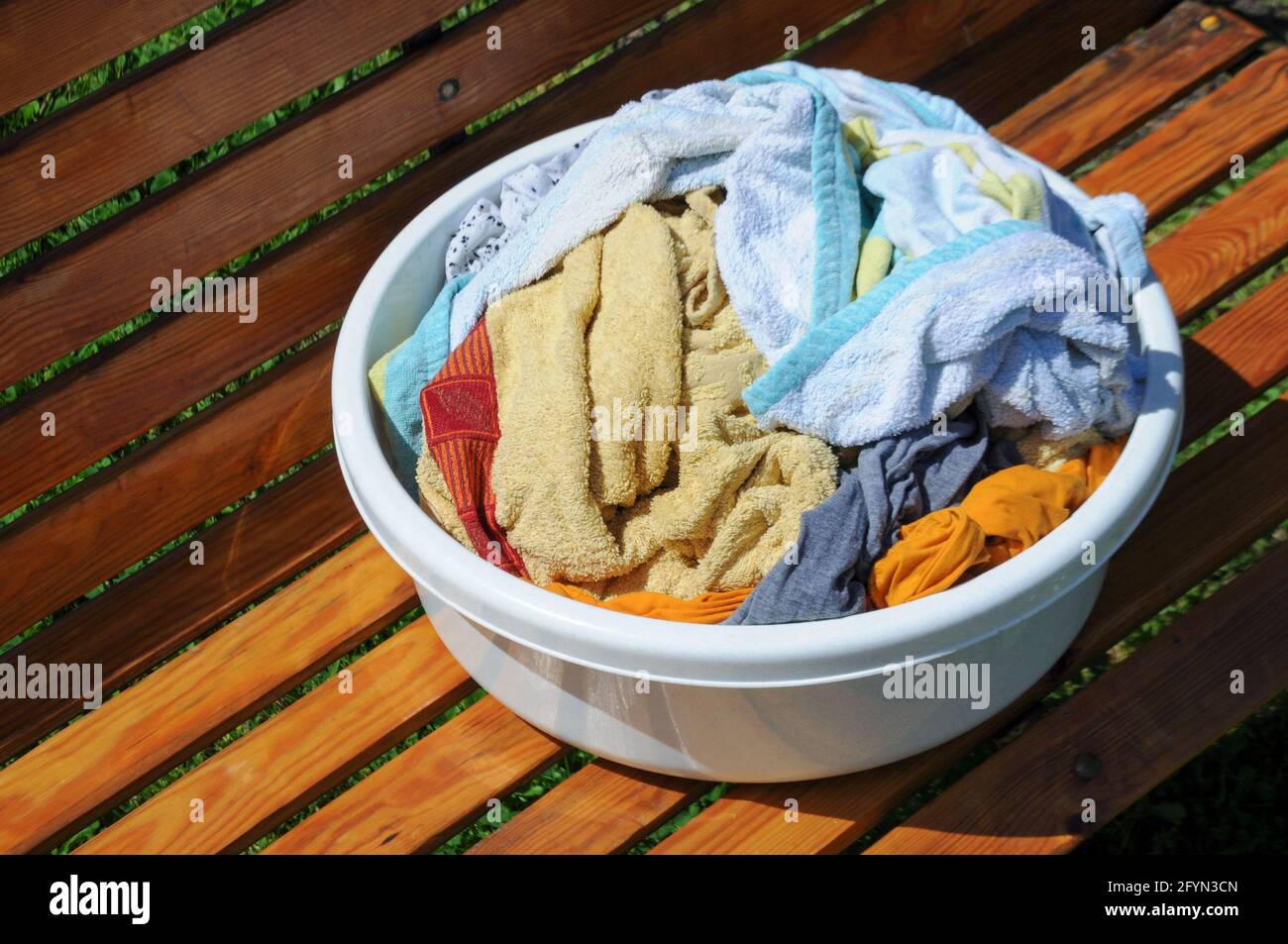 White bowl with colorful laundry on a wooden background outdoor Stock Photo