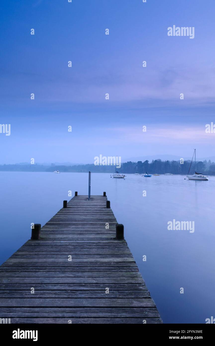 View from small wooden jetty (boat moorings, calm water, boardwalk, dramatic blue hour evening light) - Windermere, Lake District, Cumbria England UK. Stock Photo