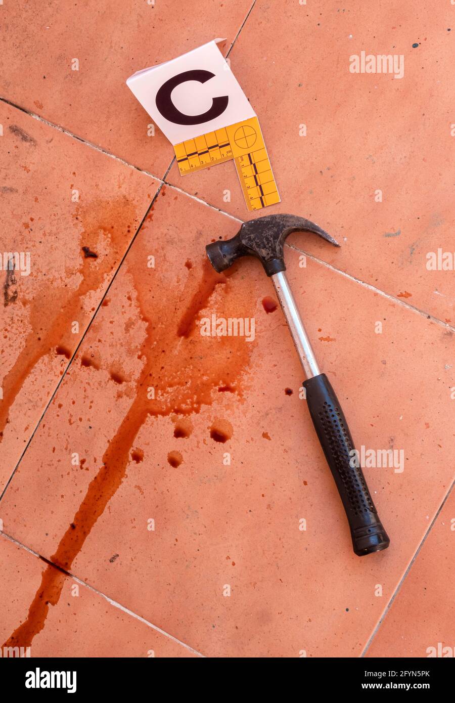 Bloody hammer on the ground marked with number, crime scene, conceptual image Stock Photo