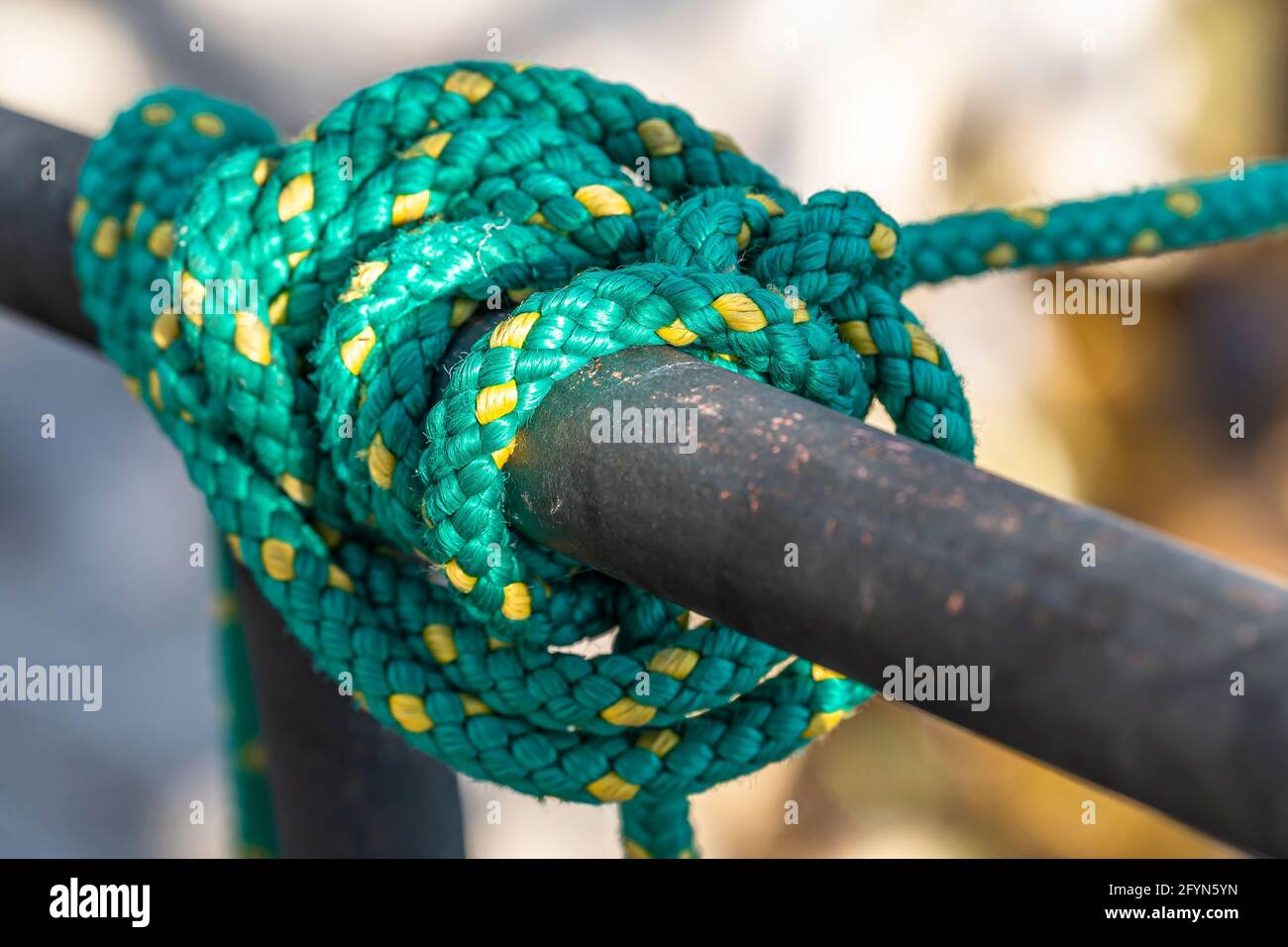 Green fishing nylon rope for mooring boats wrapped around a metal fence