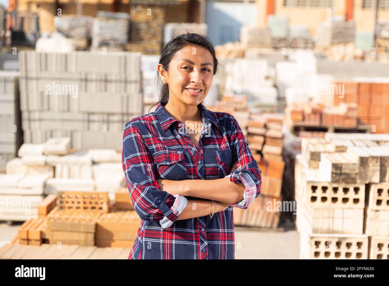 Smiling hispanic woman worker posing at building materials warehouse Stock Photo