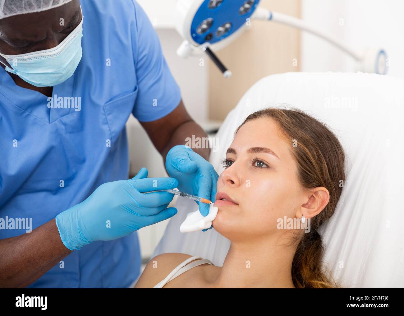 Young woman receiving injections for face skin tightening from ...