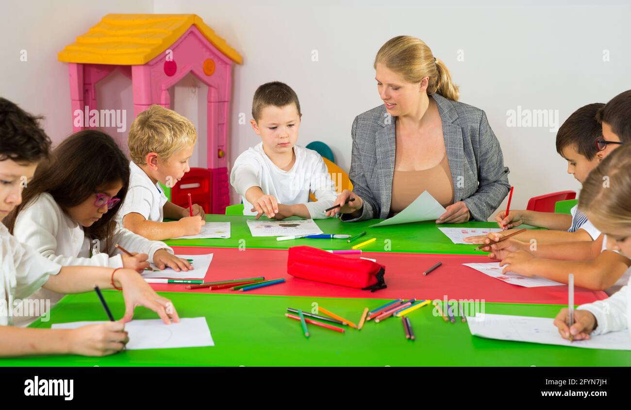 Cute schoolchildren drawing with teacher in classroom Stock Photo - Alamy
