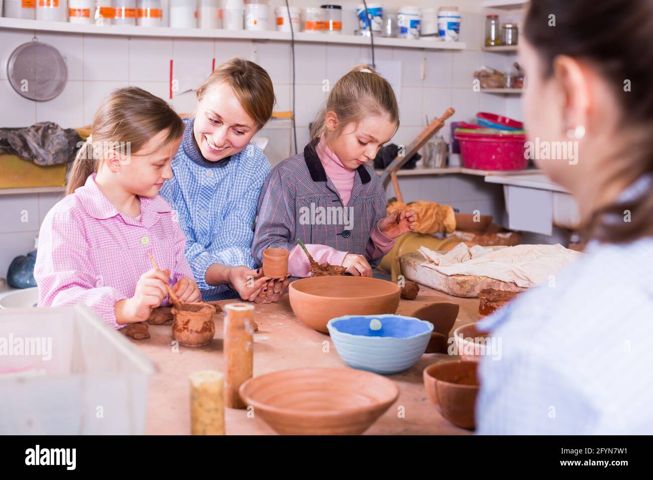 Young teacher shows the female students how to work with clay in the ceramics class Stock Photo