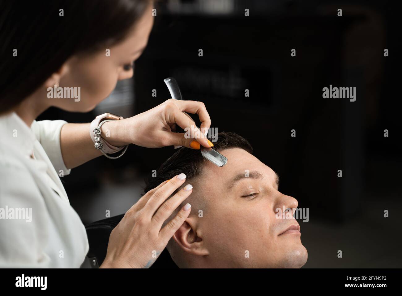 Straight razor cut man hair in barbershop. Attractive woman barber making  hairstyle for handsome man Stock Photo - Alamy
