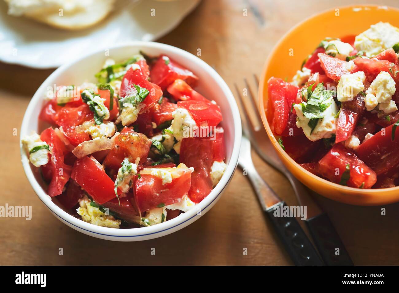 Tomatoes, feta basil salad with roll Stock Photo