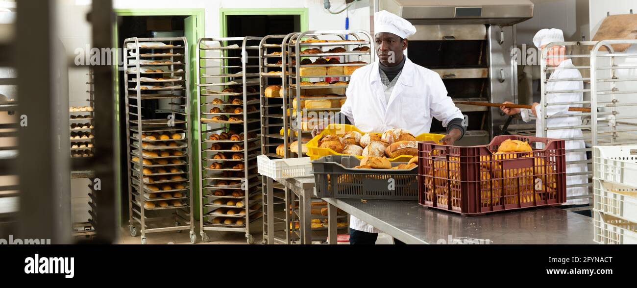 Two experienced bakers arranging fresh baked bread in small bakery Stock Photo