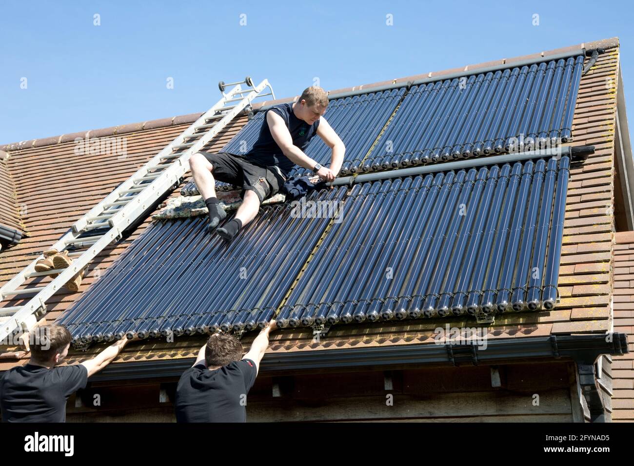 Heating engineer installing evacuated solar thermal collecting tubes on ...