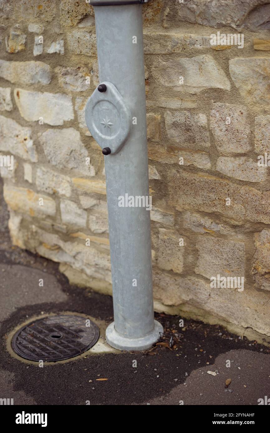 Vertical shot of a sewerage pipe and hatchway next to an old stone wall Stock Photo