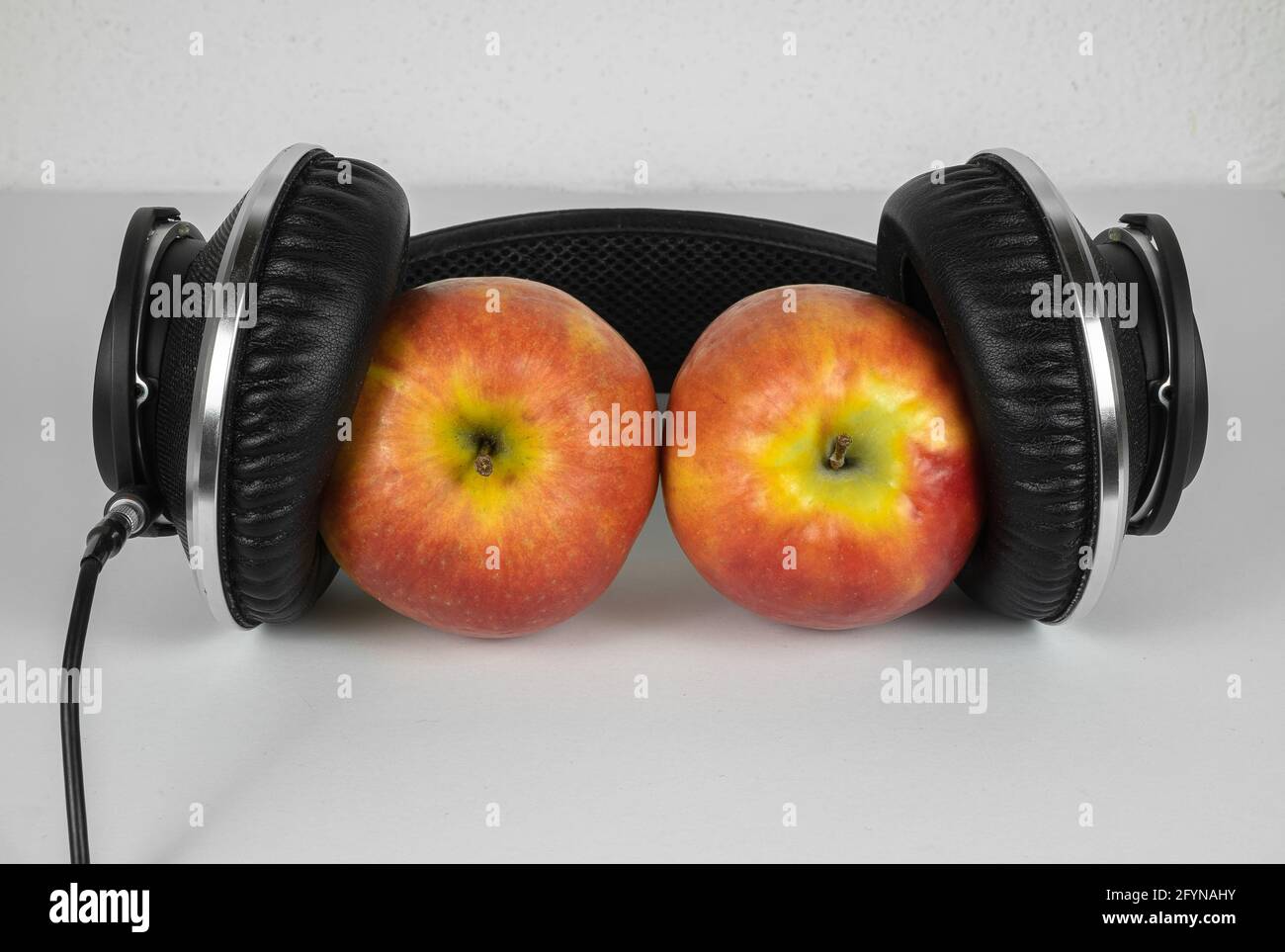 Two ripe and juicy apples between the modern studio headphones Stock