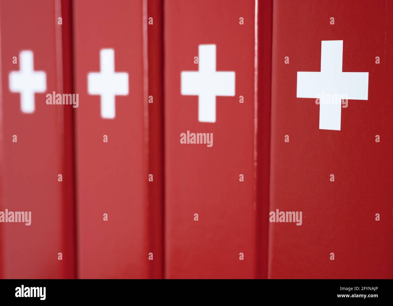 Red folders with a white cross - imitation of a swiss flag in office environment Stock Photo