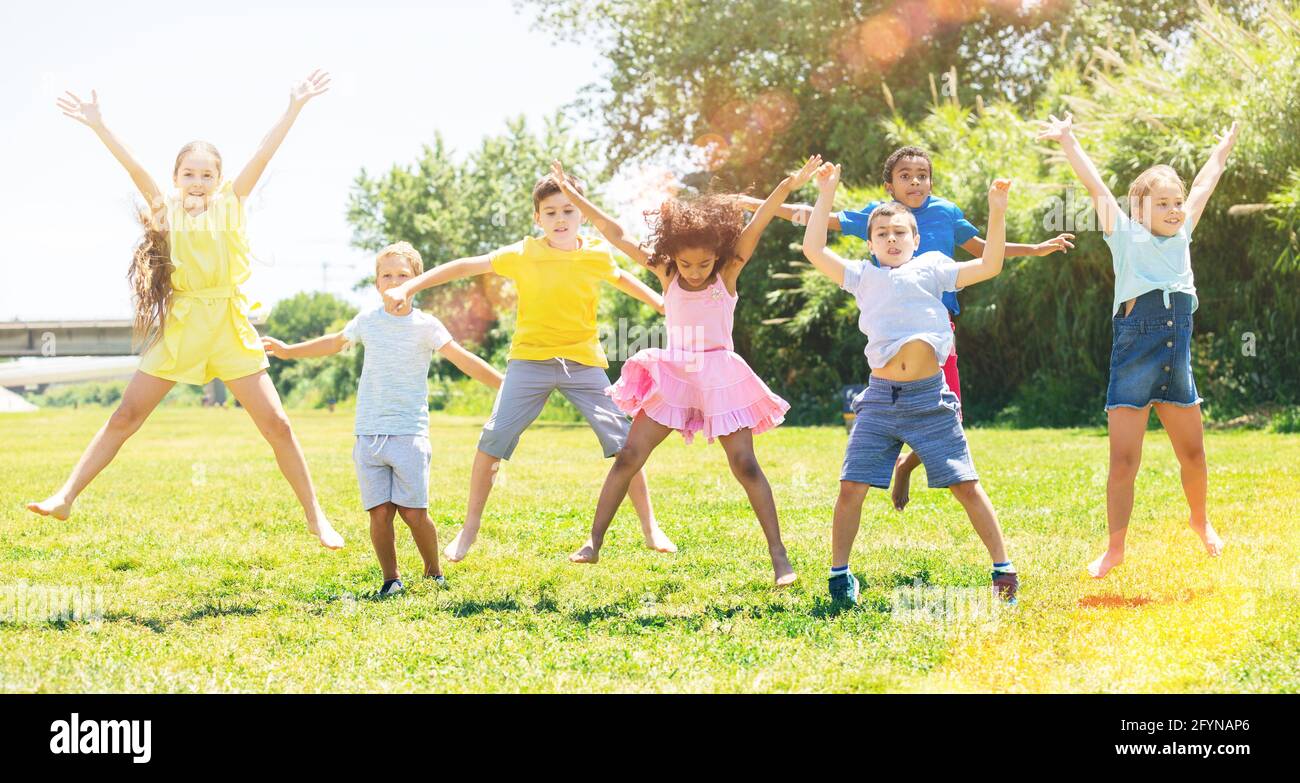 Group of happy schoolchildren jumping and smiling together in park ...