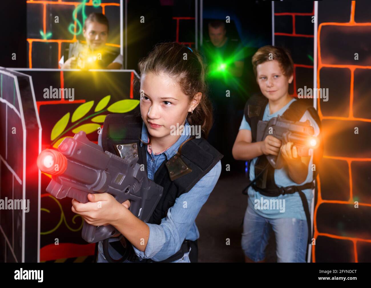 Nice girl aiming laser gun at other players during laser tag game in dark  room Stock Photo - Alamy